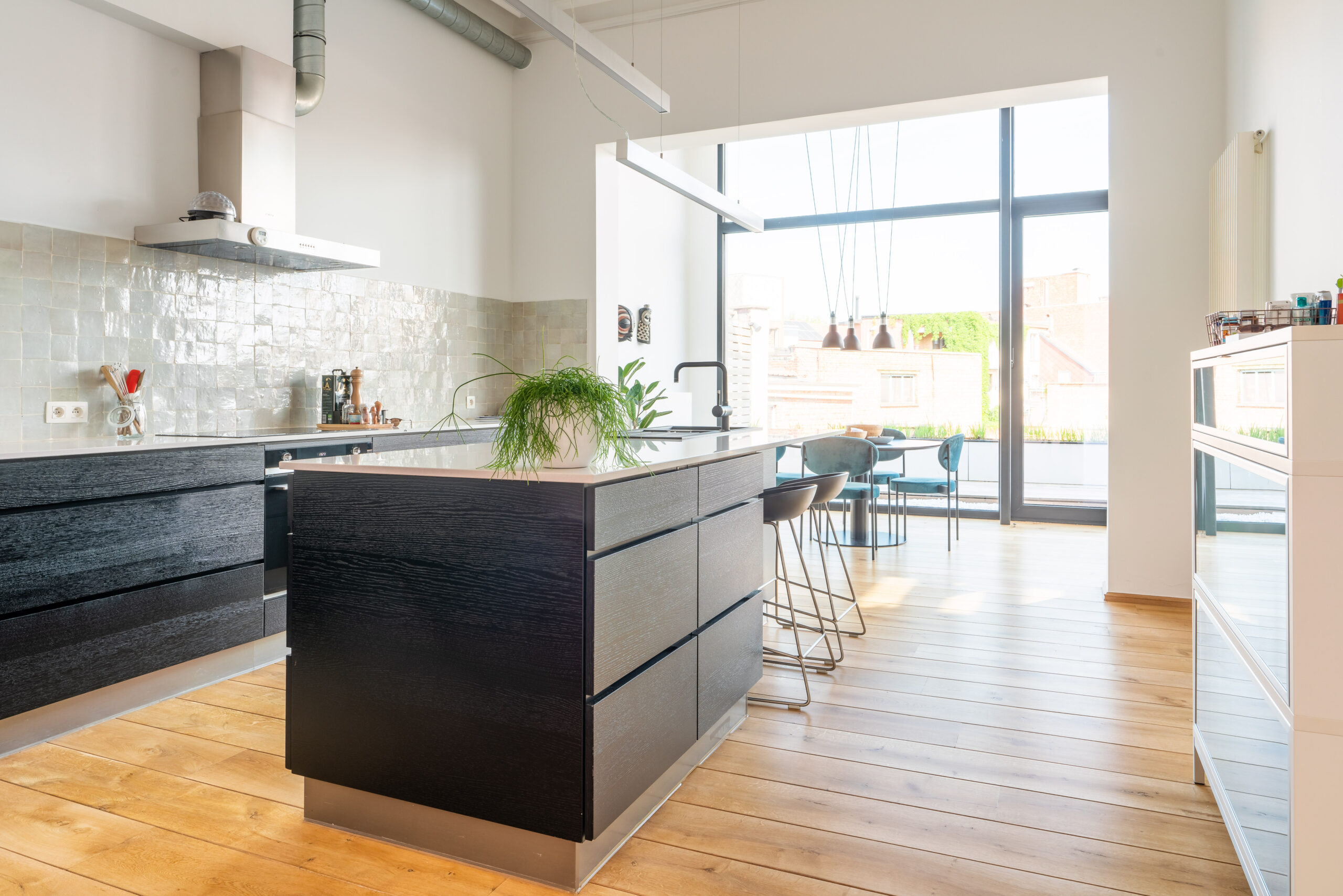 Zwarte open keuken met keukeneiland, parketvloer en grote ramen